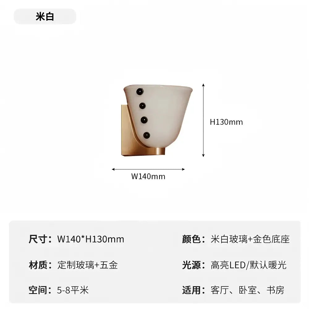 A sleek cream glass wall lamp with black dots and a gold-toned metal base for bedroom decorbites cream glass use