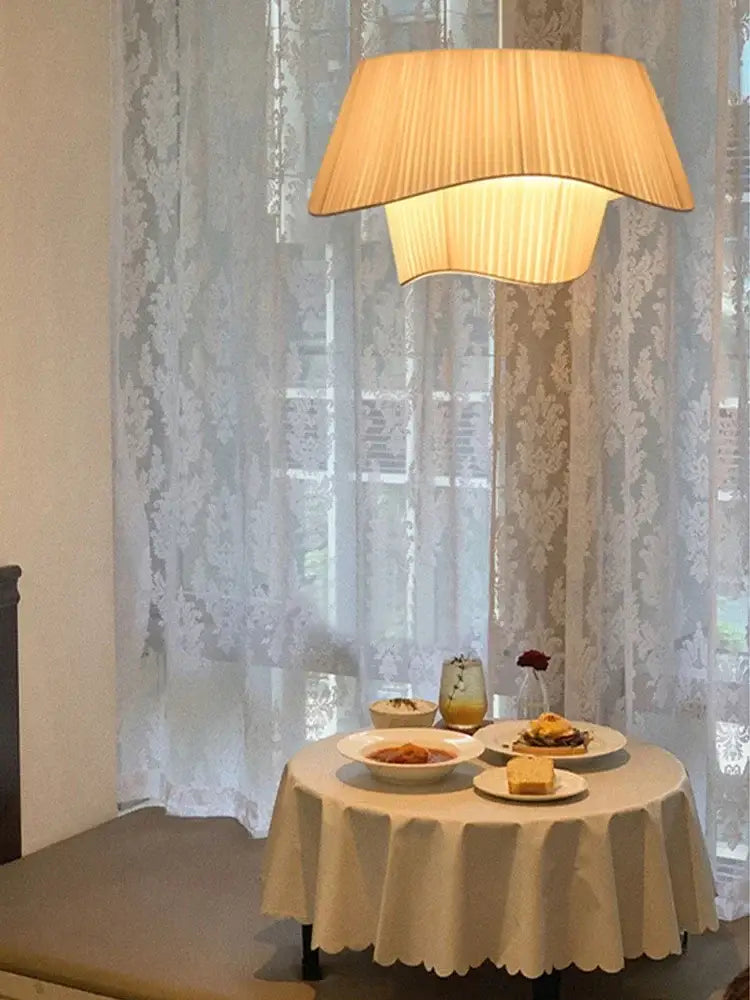 A warm beige pleated pendant light with layered designer led fabric hangs above a breakfast table decorbites designer led