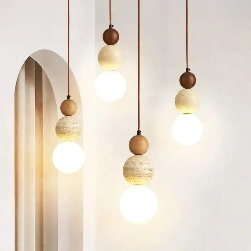 Modern pendant light with cream stone and wood accent featuring warm spherical bulbs and copper cords for dining room