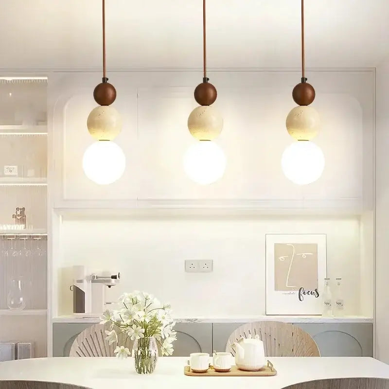 Three modern pendant lights with cream stone and matte brown wood accent spheres for dining room lighting