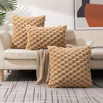 Three beige modern cream textured pom pom decorative pillow covers with raised pattern on a light-colored sofa