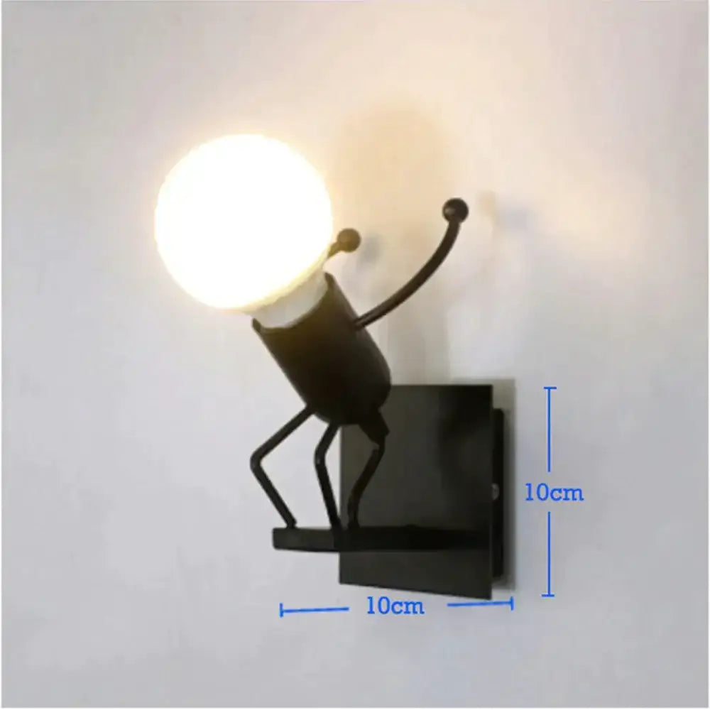 Black metal wall sconce shaped like a whimsical robot ant holding a glowing bulb for modern creative minimalism decor