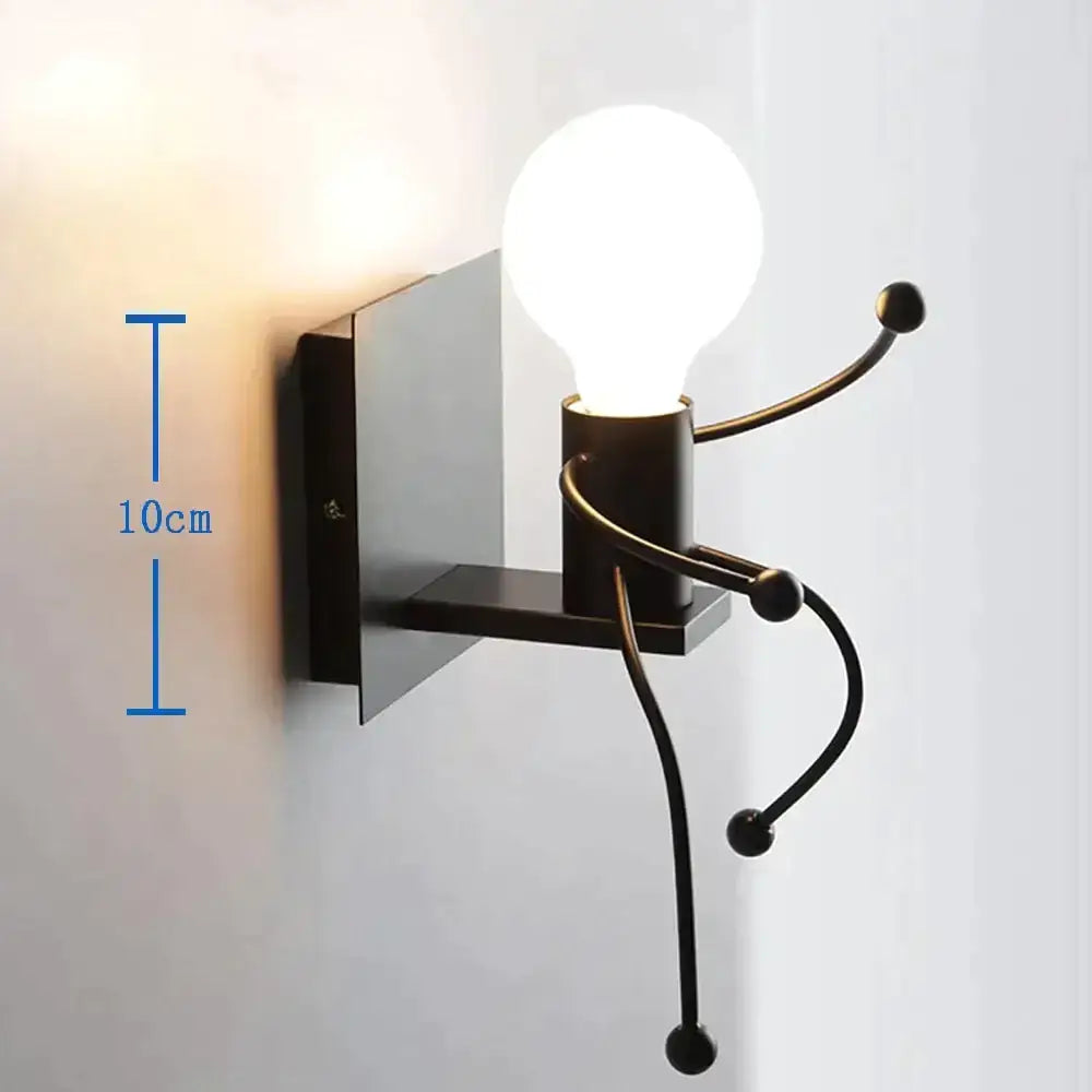 Black metal wall sconce resembling a minimalism metal robot ant with articulated limbs and exposed bulb for bedroom use