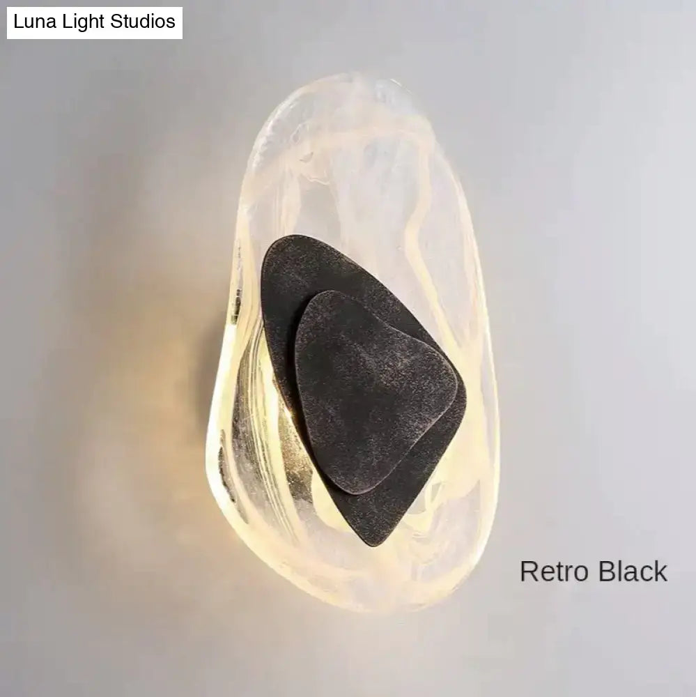 Modern creative minimalist black wall sconce with amber glass body and layered metal accents for bedroom bedside lighting