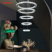 A modern multi-tiered decorbites crystal chrome led chandelier with cascading crystal rings and chrome led pendant frame