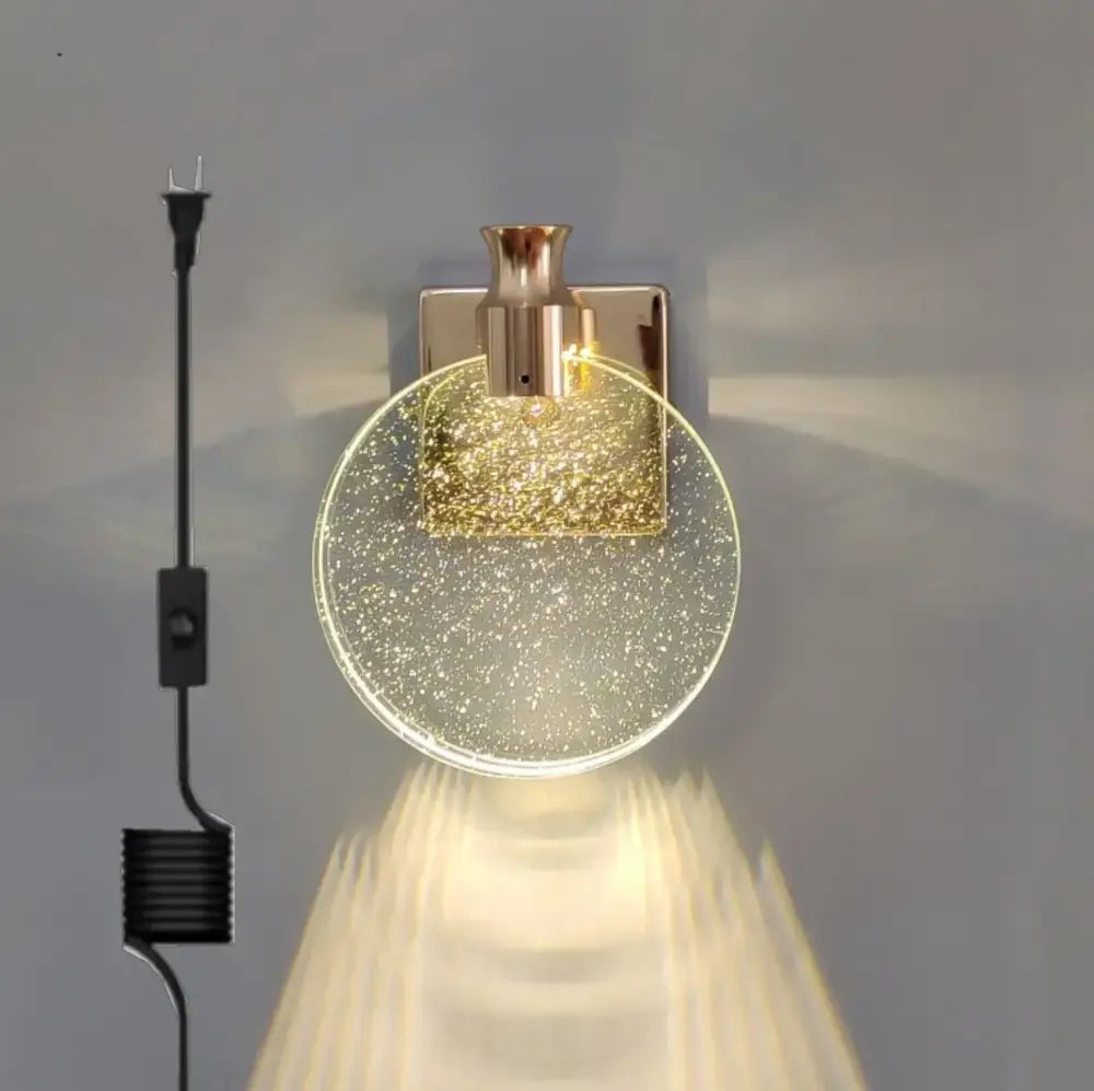 A modern wall lamp with a circular crystal glass gold shade filled with glitter and rose gold decorbites crystal glass base