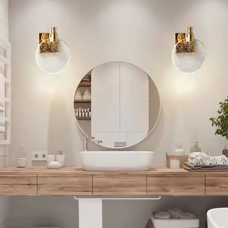 Modern crystal glass gold wall lamp with gold-toned sconces and clear sparkling glass globes flanking mirror above sink