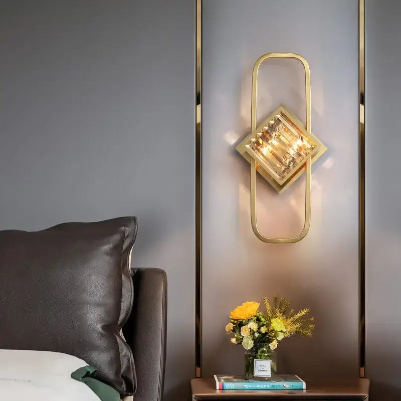 Gold-toned geometric wall lamp with faceted crystal centerpiece and glass shade for modern bedroom décorbites crystal gold wall
