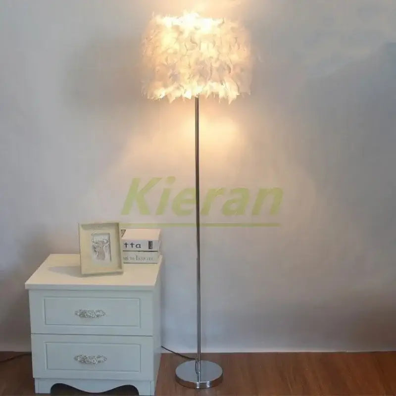 A tall slender floor lamp with a soft white feather shade and polished chrome finish for decorbites crystal led lighting