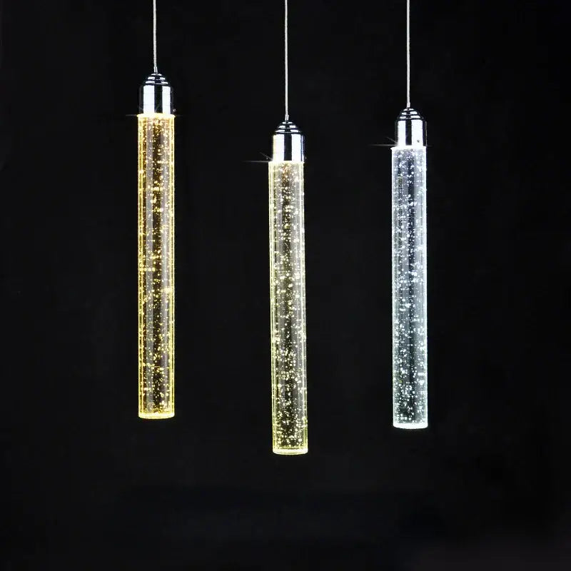 Three modern cylindrical decorbites crystal led pendant lights with chrome tops and glowing clear glass for dining room decor