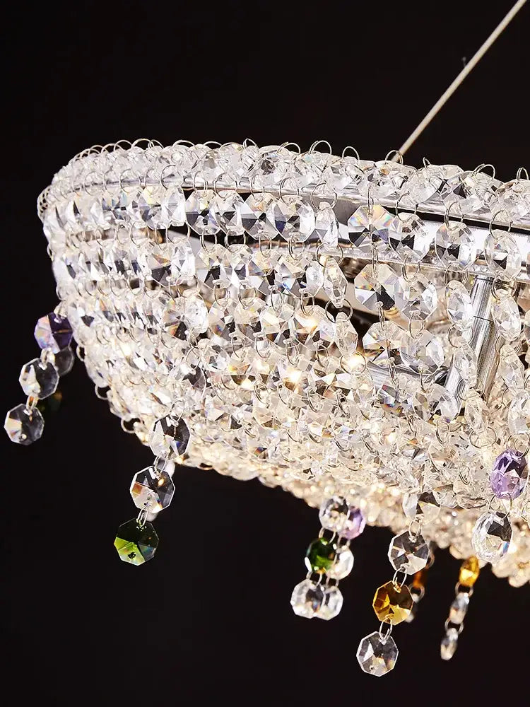 A modern decorbites crystal oval chandelier with a silver frame and clear and red faceted beads for living room decor