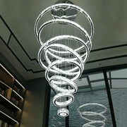 A modern decorbites crystal ring led chandelier with multiple clear crystal and chrome spiral rings for dining room lighting