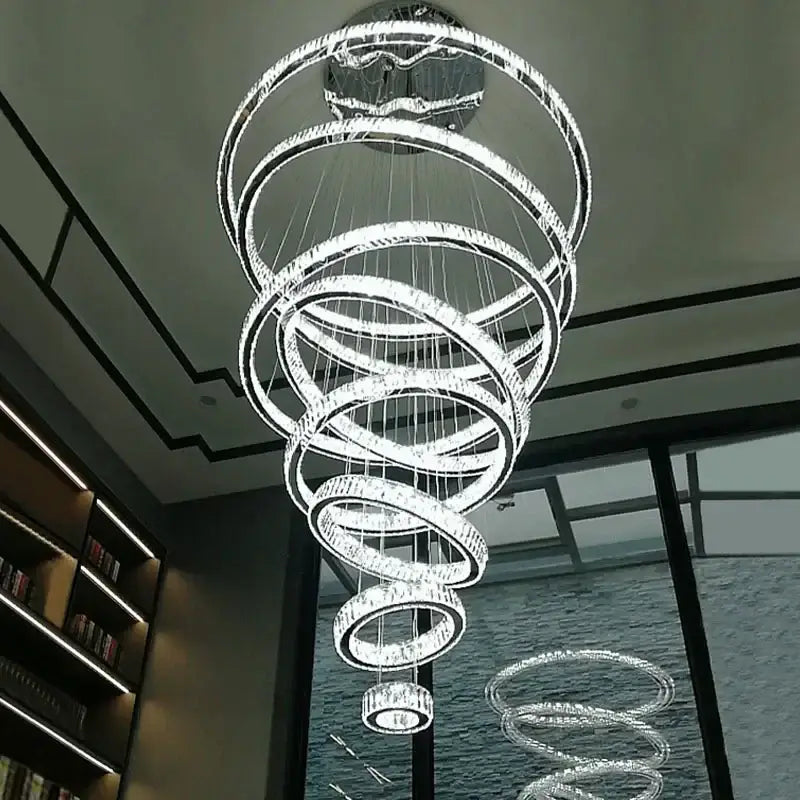 A modern decorbites crystal ring led chandelier with multiple clear crystal and chrome spiral rings for dining room lighting