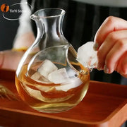 Modern crystal sake ice jug made of clear glass filled with amber liquid and ice cubes for decorbites crystal sake use