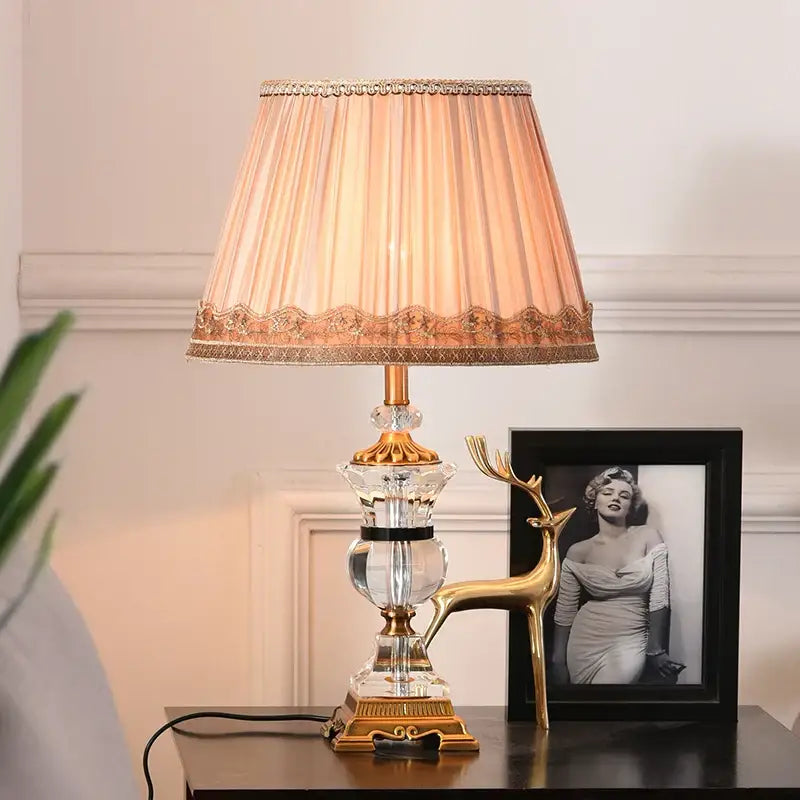 Elegant decorbites crystal table lamp with gold tone base and peach pleated fabric shade with cream lace trim