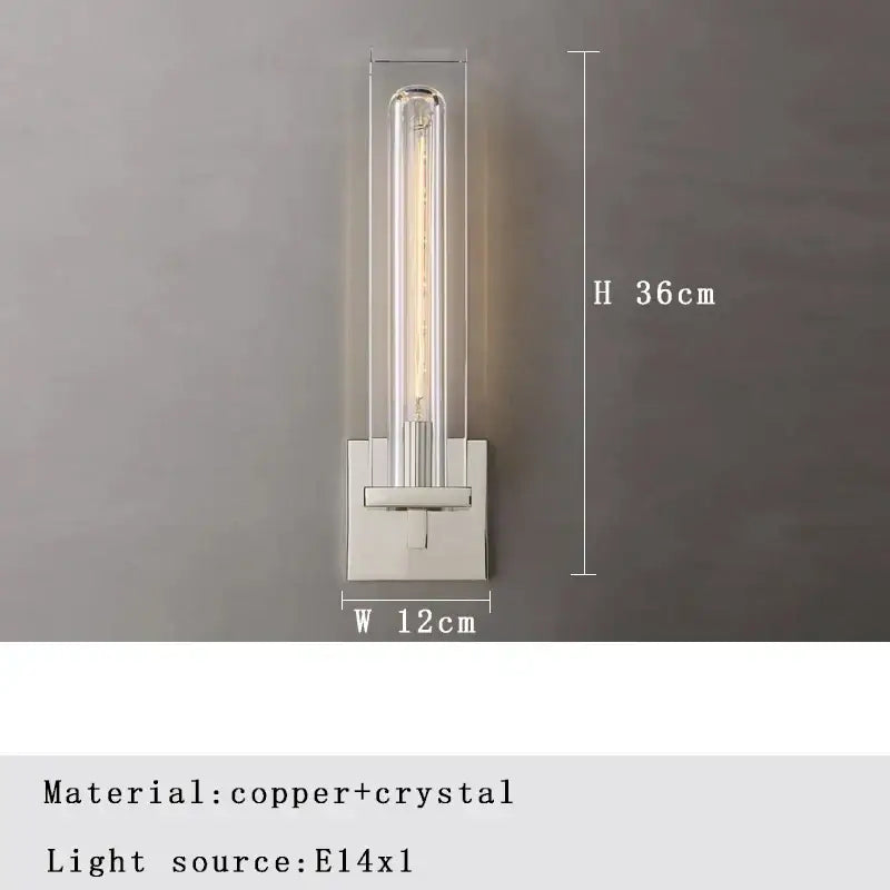 A modern crystal wall lamp with a clear crystal tube and polished copper base for elegant bedroom decorbites wall lamp