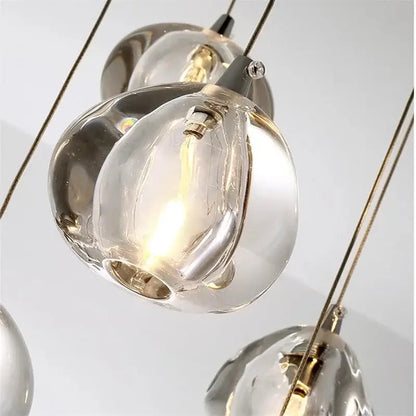 Modern crystal water droplet chandelier with clear hand-blown glass and metallic accents emitting a warm glow