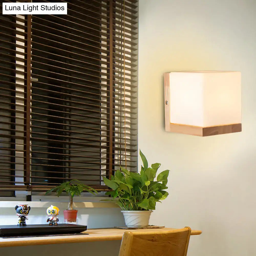 Modern cube shaped sconce wall lamp featuring a frosted glass panel and wooden backplate for bedroom lighting