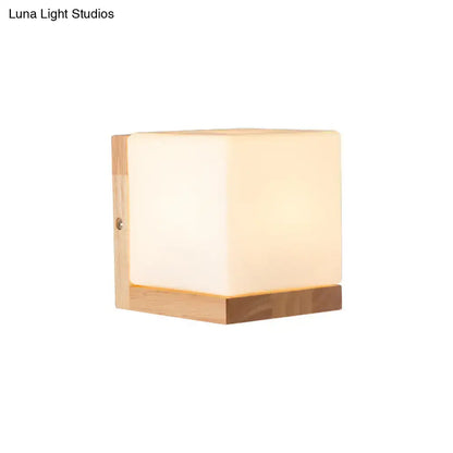 Modern cube shaped sconce wall lamp with warm frosted acrylic face and wooden backplate for bedroom lighting