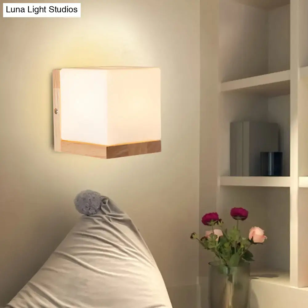 Modern cube shaped wall lamp with frosted glass panel and wooden backplate for minimalist bedroom lighting
