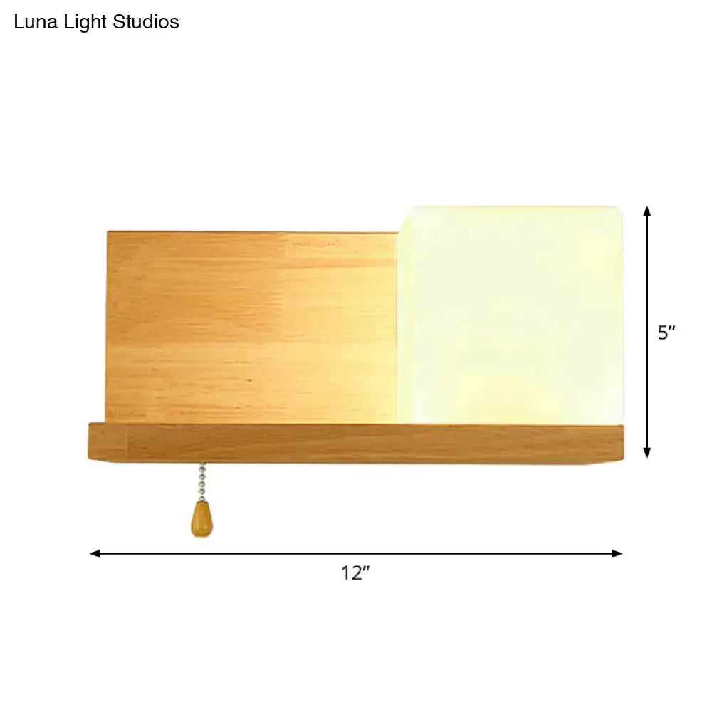 Modern cubic wall sconce light with beige wood finish and frosted glass shade featuring a pull chain for bedroom use