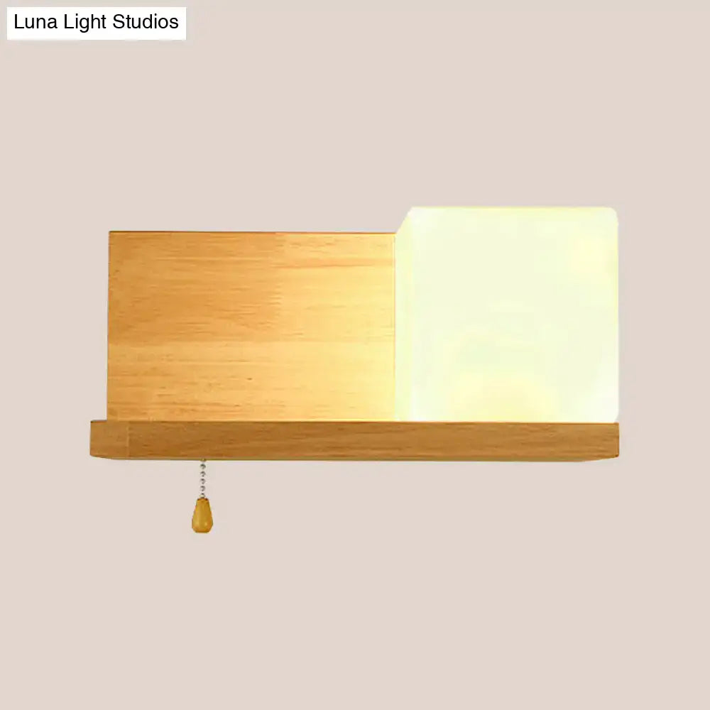 Minimalist cubic wall sconce light with beige wood frame, frosted glass diffuser, and wooden pull chain for bedroom