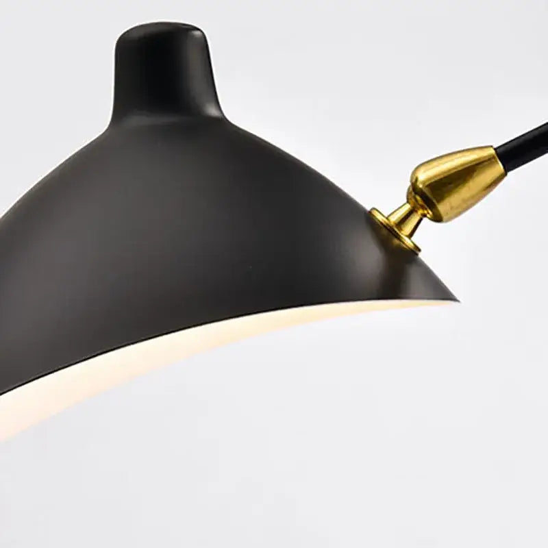 Modern curved black metal floor lamp with black matte lampshade and gold-toned joint by decorbites black metal floor