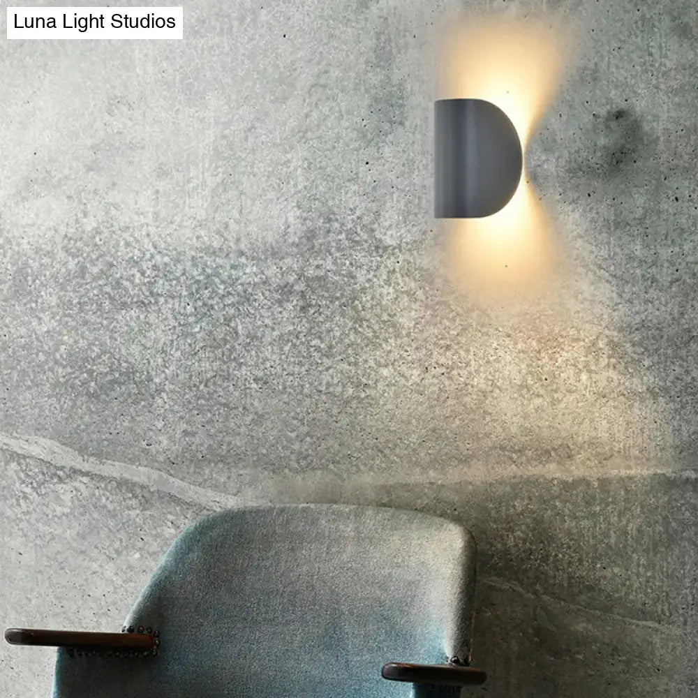 Modern curved gold wall sconce light with matte gray half-moon design casting warm glow for bedroom ambient lighting