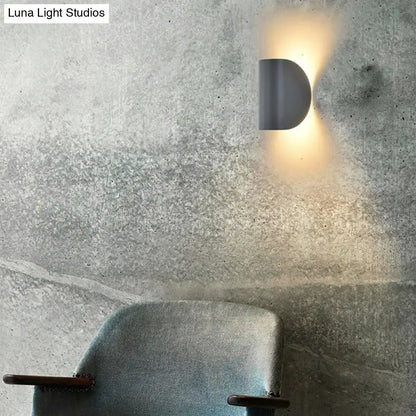 Modern curved gold wall sconce light with matte gray half-moon design casting warm glow for bedroom ambient lighting