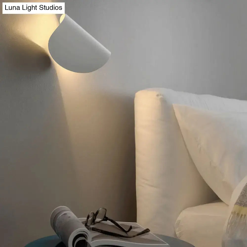 A sleek minimalist white wall sconce light with a curved modern design ideal for bedroom ambient lighting