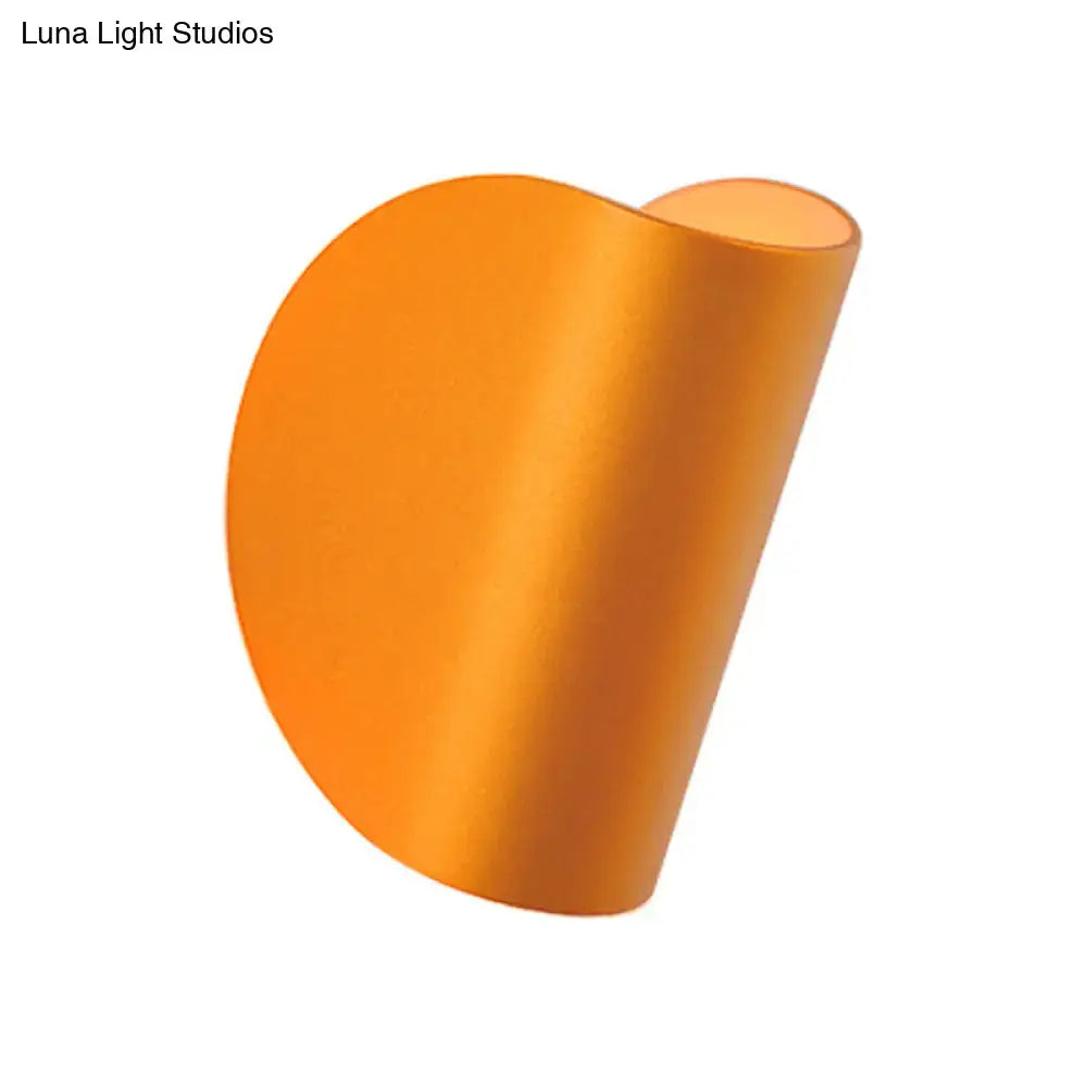 A sleek curved orange satin finished wall sconce light for modern bedroom ambient lighting in black grey tones