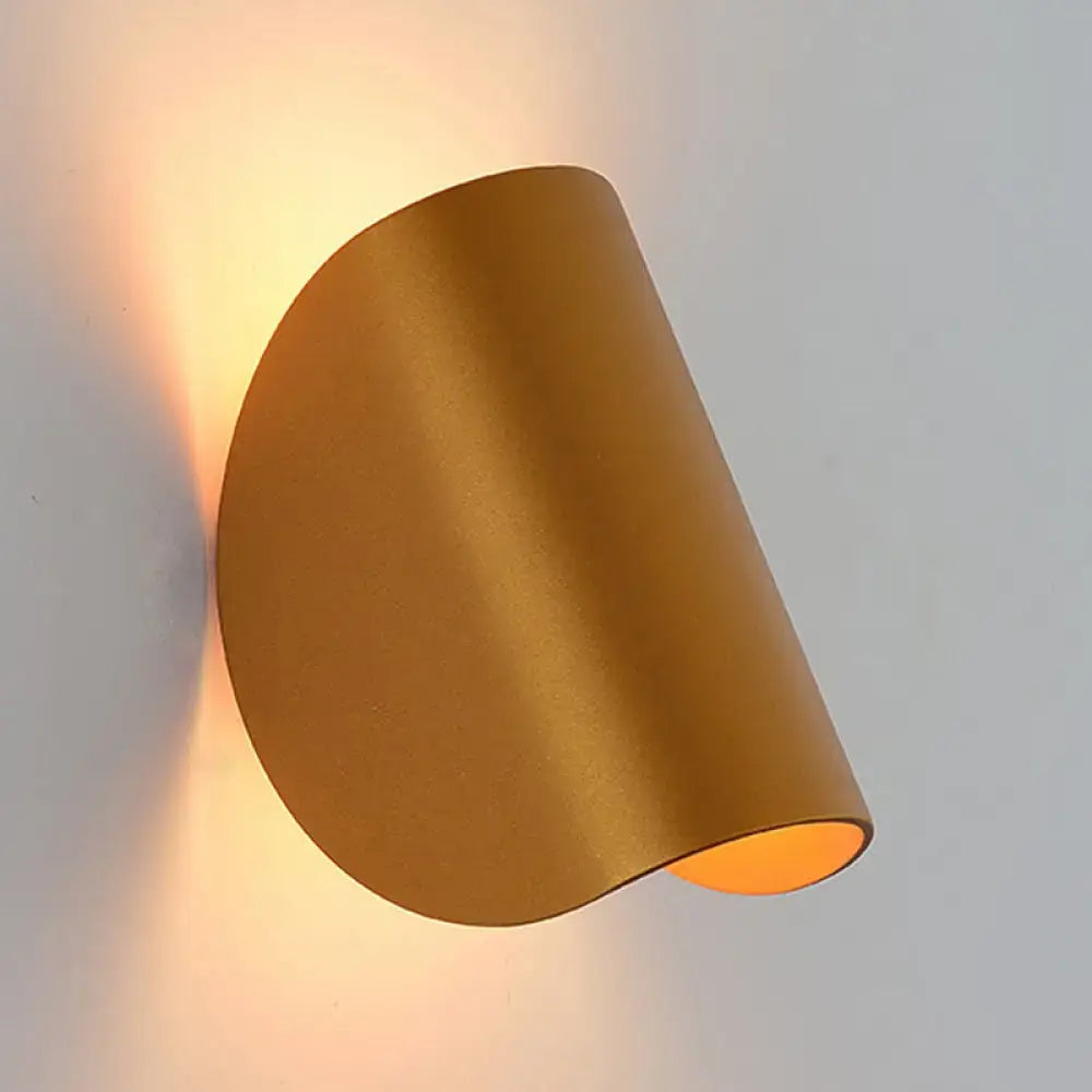 Modern curved gold wall sconce light with a sleek matte finish providing warm ambient bedroom lighting