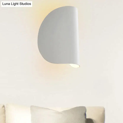 A sleek minimalist white wall sconce light with a curved half-circular design for bedroom ambient lighting