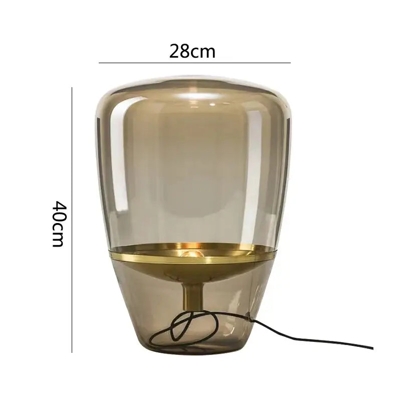 A modern decorbites glass table lamp with a translucent amber glass body and polished brass base for bedroom led lighting