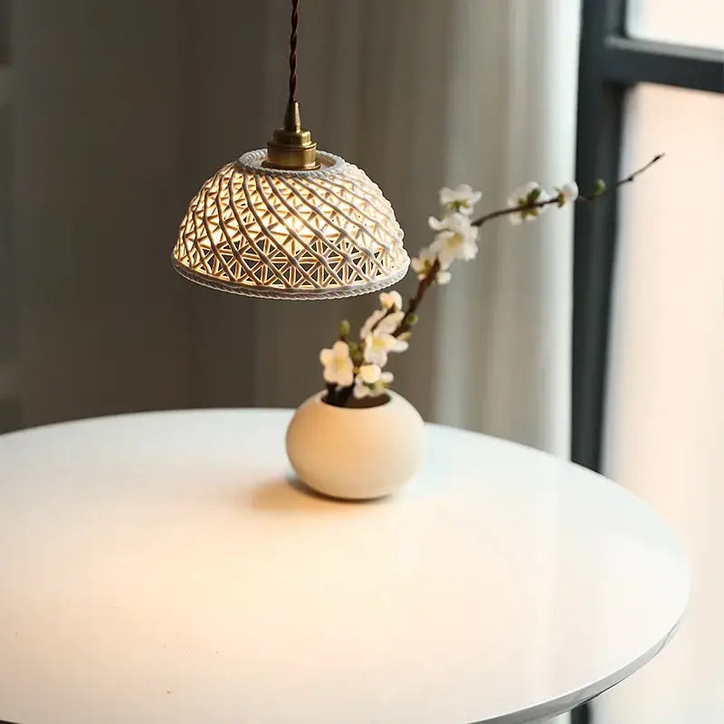 A warm woven bamboo pendant lamp with brass fixture hangs above a minimalist ceramic led pendant vase