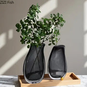 Two sleek dark gray double glass vases with smooth curves and metallic bases on wooden tray for hydroponic decor