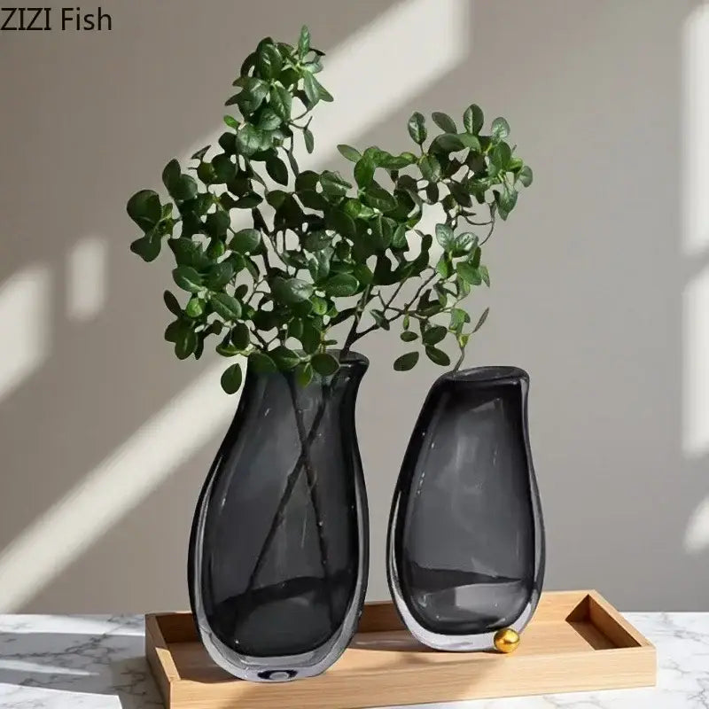 Two sleek dark gray double glass vases with smooth curves and metallic bases on wooden tray for hydroponic decor
