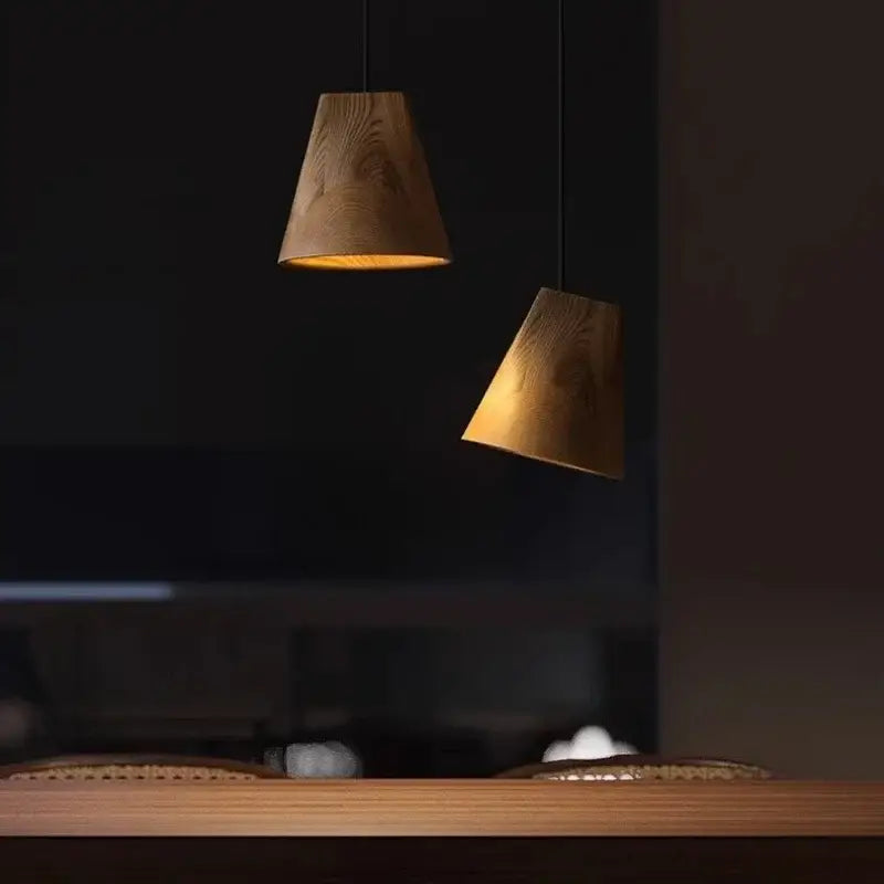 Two warm-toned wooden pendant lights with natural wood grain hang from black cords in a dark modern adjustable wooden chandelier