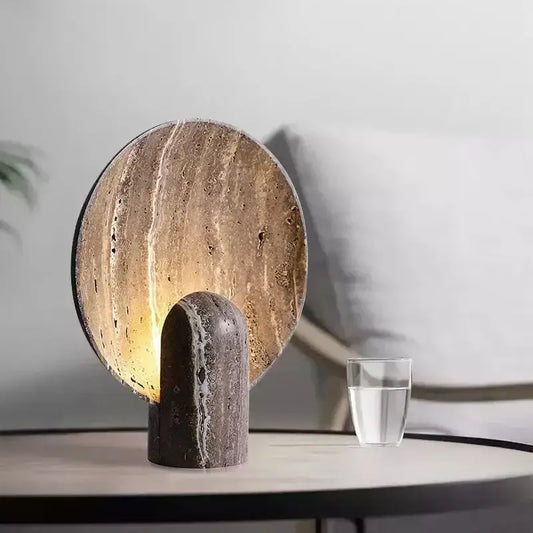 A sleek modern dark travertine rock led table lamp with a warm glow suitable for bedroom use
