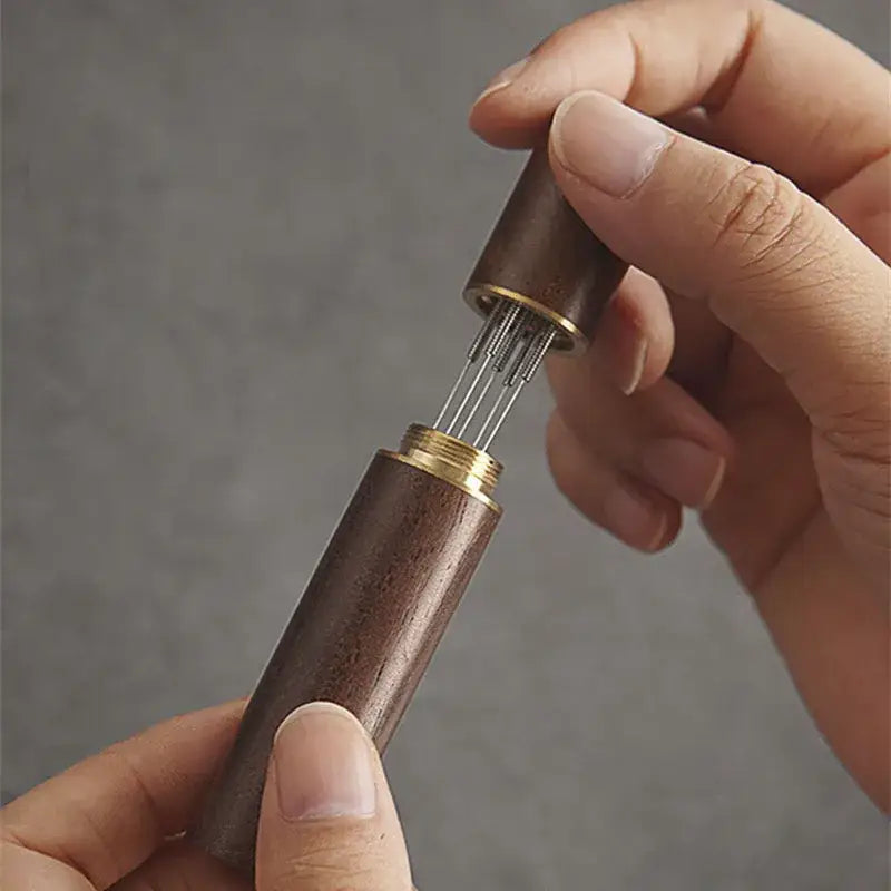Modern dark brown wooden espresso coffee stirrer case with brass fittings containing fine metal needle distributor set