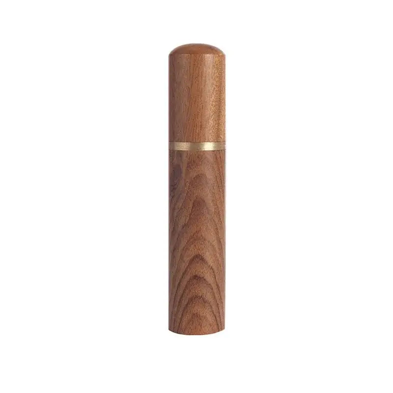A sleek cylindrical wooden espresso coffee stirrer with warm amber finish and a thin gold needle distributor band
