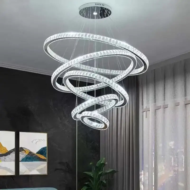 A modern decorbites gold rings crystal chandelier with multiple glowing rings suspended from a circular ceiling mount