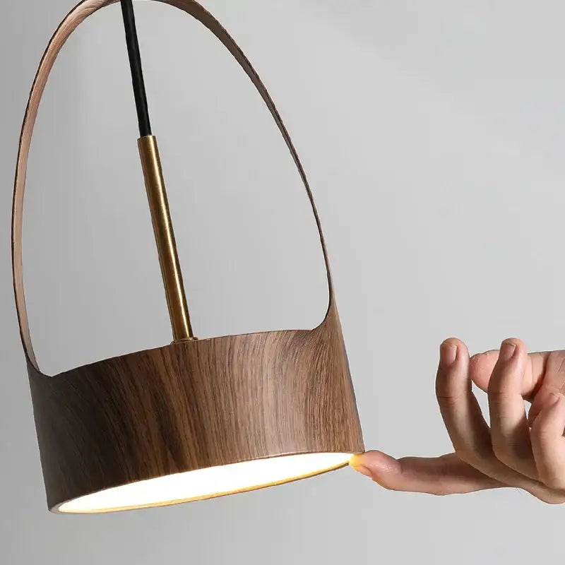 A modern decorbites led wood grain dining room pendant light with warm wooden body, curved handle, and brass accent rod