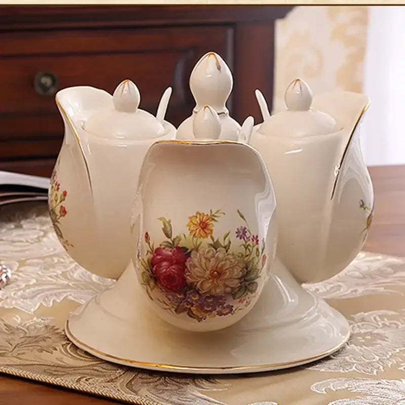 Cream-colored ceramic seasoning set with floral hand-painted designs and gold-trimmed lids featuring rotatable spice jars