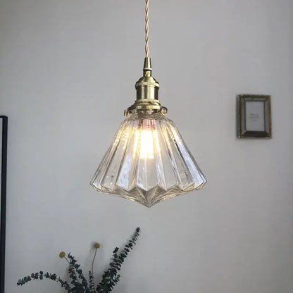 A modern diamond amber glass led pendant light with faceted glass and brass fixture for dining room lighting
