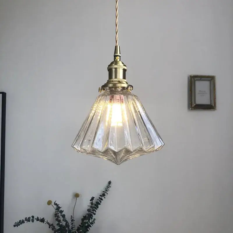 A modern diamond amber glass led pendant light with faceted glass and brass fixture for dining room lighting