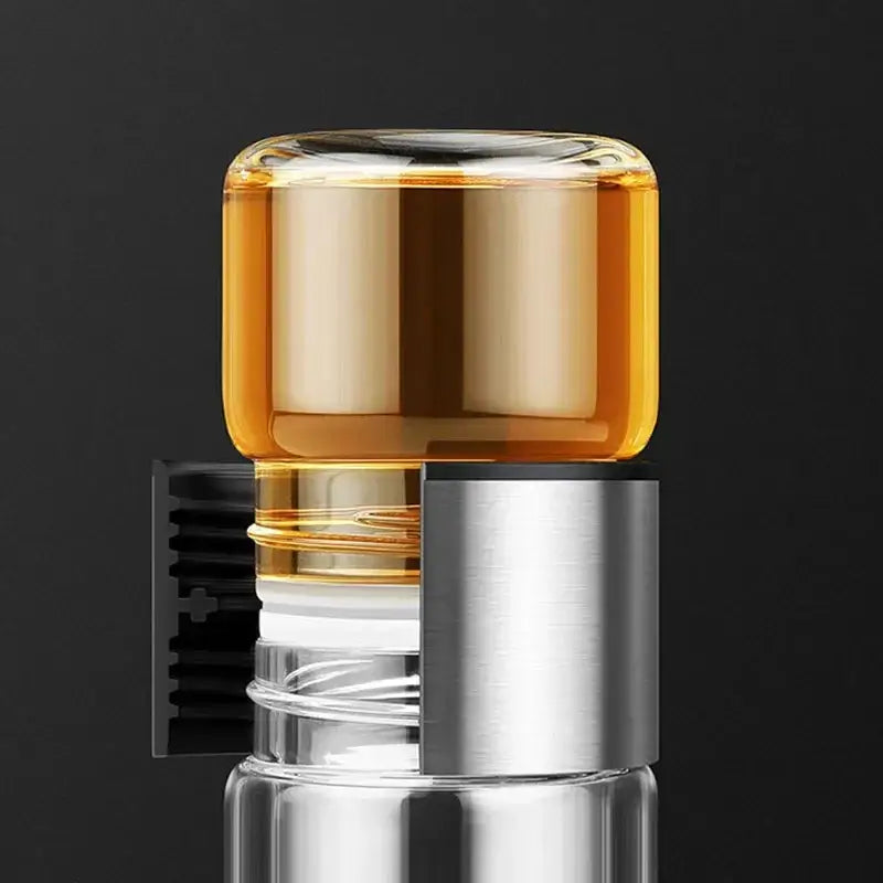 Modern double layer glass tea infuser bottle with silver cap and black clip filled with amber liquid for kitchen use