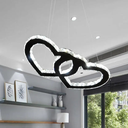 Lámpara de araña colgante LED moderna con forma de doble corazón, cristal transparente, pantalla negra y luz cálida/blanca.