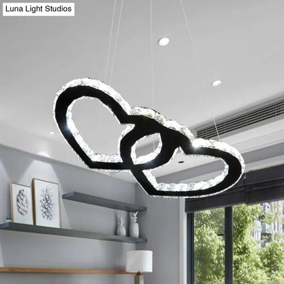 Lámpara de araña colgante LED moderna con forma de doble corazón, cristal transparente, pantalla negra y luz cálida/blanca.