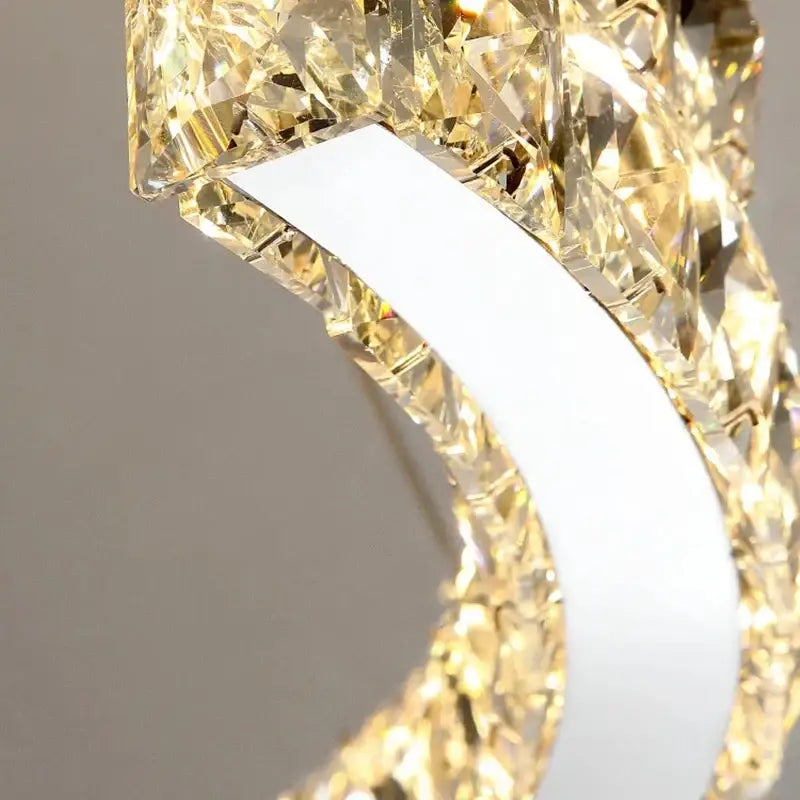 A modern double ring decorbites crystal ceiling chandelier with a white metal frame and golden faceted crystals